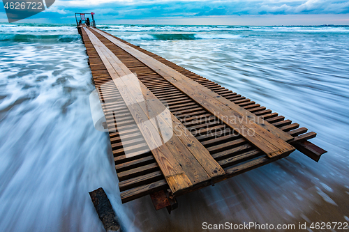 Image of Pier going to sea and sea surf after sunset