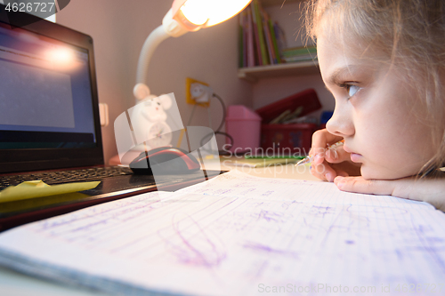 Image of A very tired girl hates watching video lessons at home