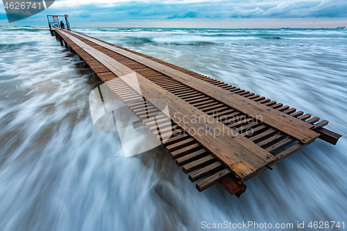 Image of Wooden pier in a storm covered with a wave, long exposure