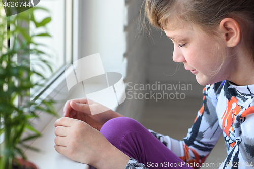 Image of Offended girl cries at the window in the room