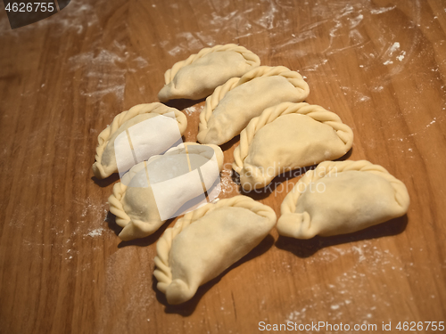 Image of Six uncooked dumplings on the wooden kitchen board