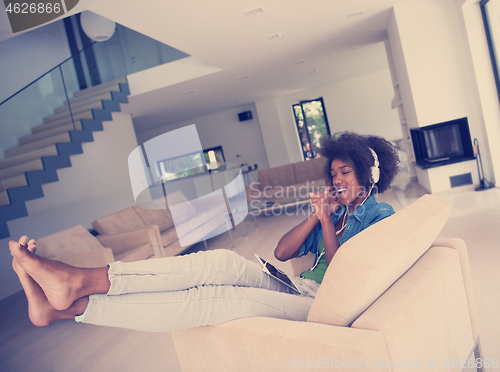 Image of African american woman at home in chair with tablet and head pho