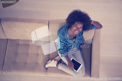 Image of african american woman at home with digital tablet top view