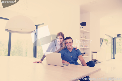 Image of couple using laptop at home