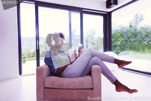 Image of African american woman at home in chair with tablet and head pho