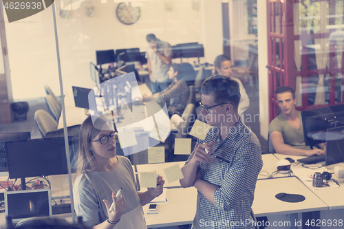 Image of young couple at modern office interior writing notes on stickers