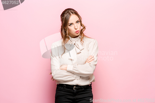 Image of The serious frustrated young beautiful business woman on pink background