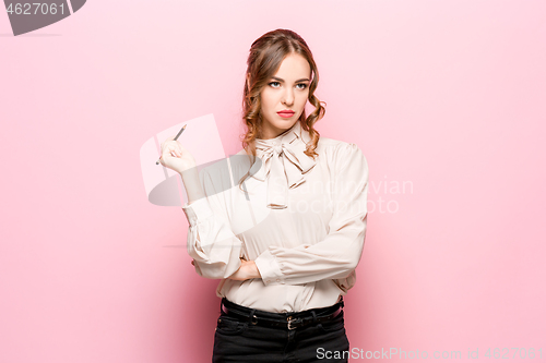 Image of The serious frustrated young beautiful business woman on pink background