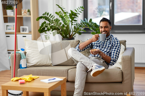 Image of indian man drinking coffee after home cleaning