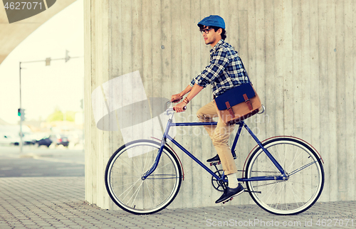 Image of young hipster man with bag riding fixed gear bike