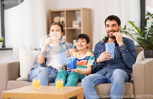 Image of happy family with popcorn watching tv at home