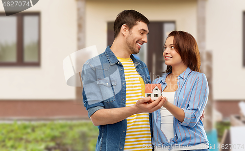 Image of smiling couple holding house model