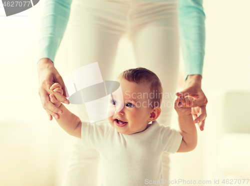 Image of happy baby learning to walk with mother help