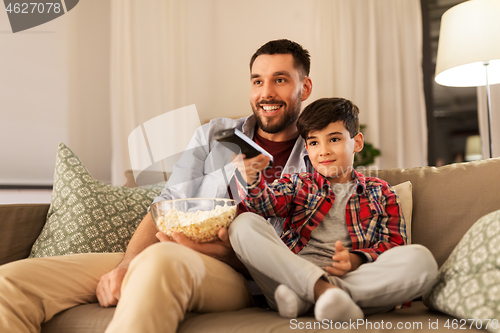 Image of father and son with popcorn watching tv at home