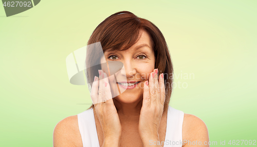 Image of portrait of smiling senior woman touching her face