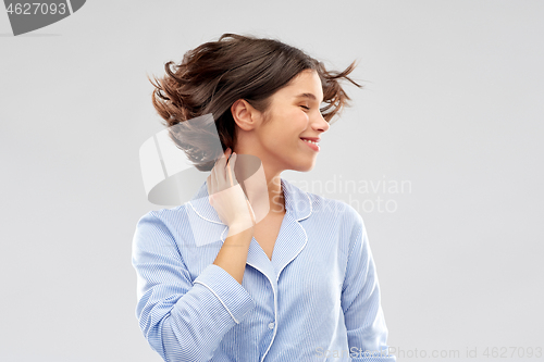 Image of happy young woman in pajama over grey background