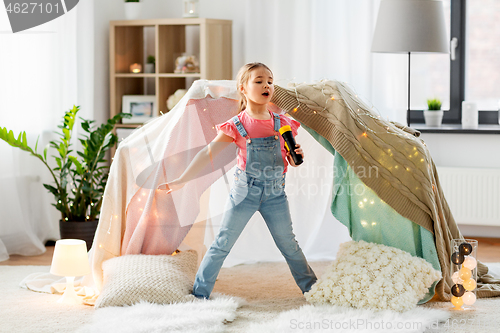 Image of little girl with toy microphone singing at home