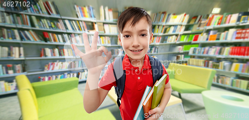 Image of student boy with books showing ok at library