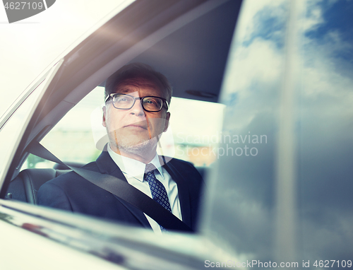 Image of senior businessman driving on car back seat