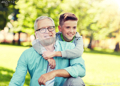 Image of grandfather and grandson hugging at summer park