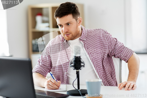 Image of audio blogger with laptop, microphone and notebook