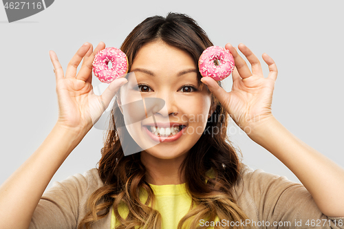 Image of happy asian woman with donuts