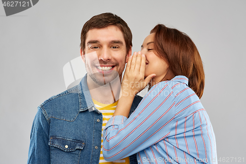 Image of happy couple whispering over grey background