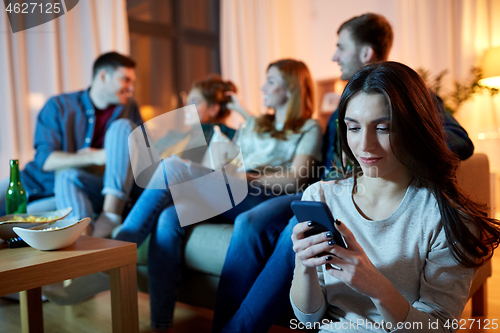 Image of young woman with smartphone at home party