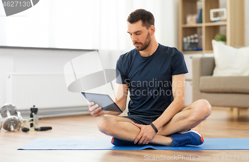 Image of man with tablet computer on exercise mat at home