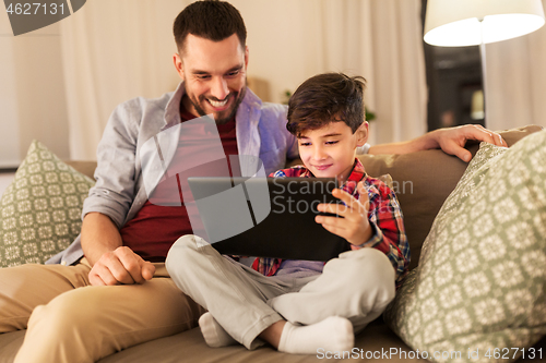 Image of father and son with tablet pc playing at home