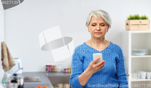 Image of senior woman using smartphone at kitchen