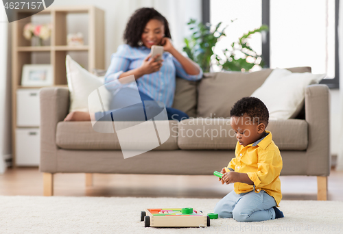 Image of baby playing toy blocks and mother with smartphone