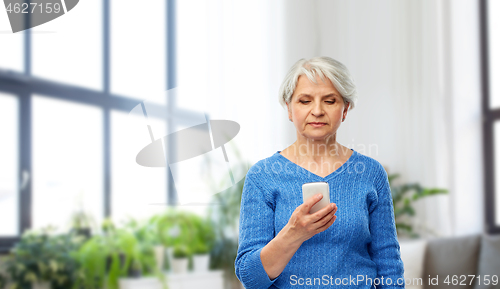 Image of senior woman using smartphone at home