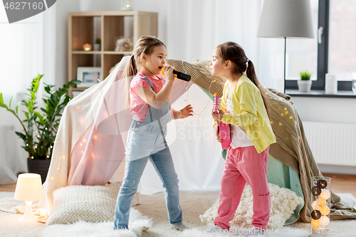 Image of girls with guitar and microphone playing at home