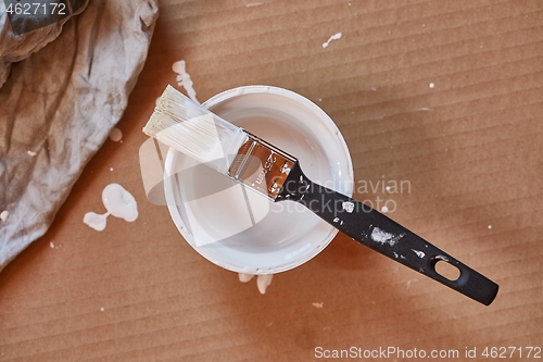 Image of Paint brush on a can of white wall paint