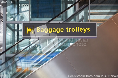 Image of Airport terminal signs, luggage trolleys