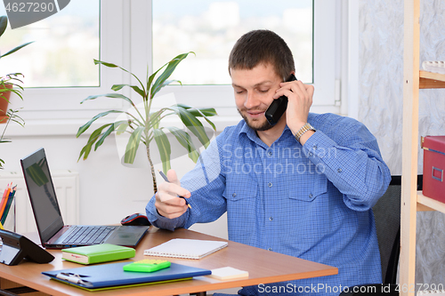 Image of Office specialist talking on the phone and taking notes in a notebook