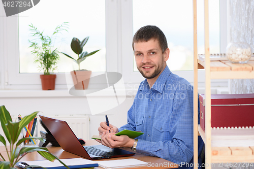 Image of The office specialist writes in a diary and looked into the frame
