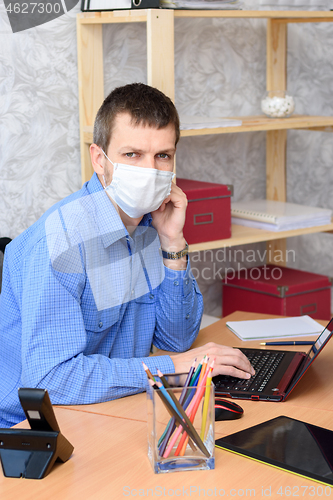 Image of Worker working remotely in a computer in a medical mask looked into the frame