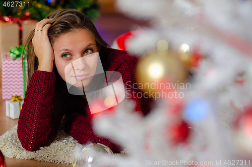 Image of portrait of a beautiful brooding girl behind a Christmas tree