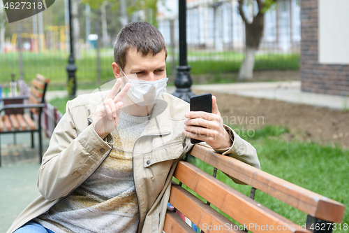 Image of A man in the park communicates with friends via video calling