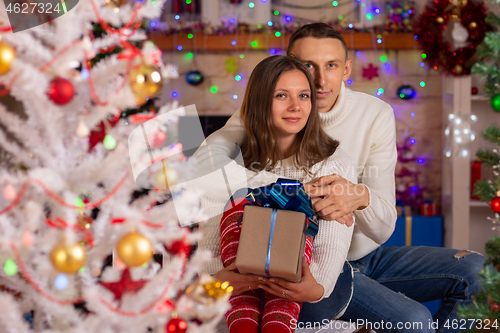 Image of A couple in love with gifts near a Christmas tree