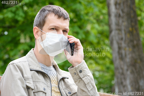 Image of Portrait of a man in a medical mask talking on the phone