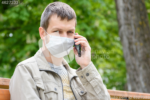 Image of Close-up of a masked man with a phone on the street, looked into the frame