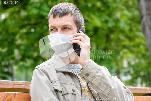 Image of Close-up of masked man with phone on the street