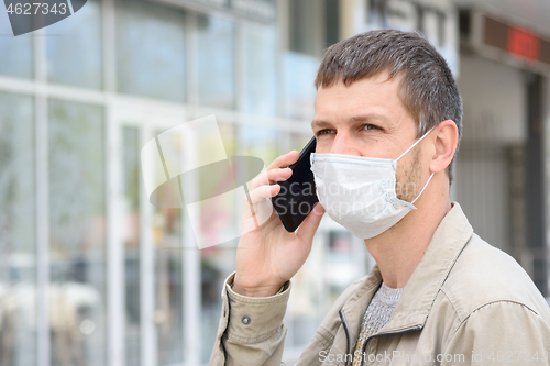 Image of Portrait of a masked man with a mobile phone in the background of the store