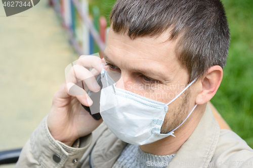 Image of Close-up of a man in a medical mask talking on the phone