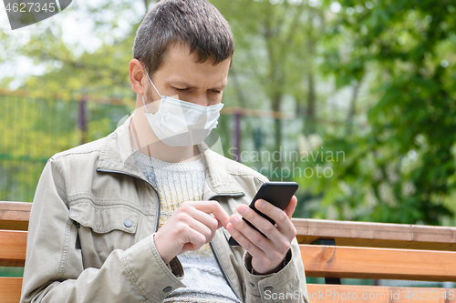 Image of A man on a walk looks at the screen of a mobile phone