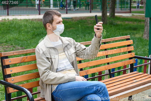 Image of A man walking in the park with a mobile phone