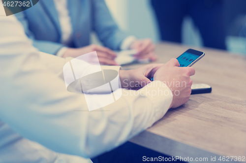 Image of Young casual businessman using smartphone